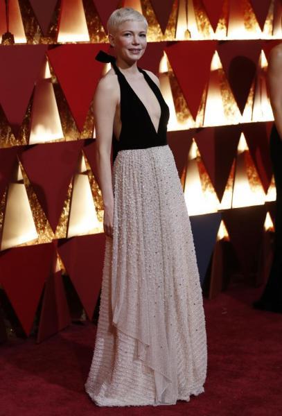 La actriz Michelle Williams, quien apareció en la alfombra con un modelo bicolor en dorado y negro de tirantes.