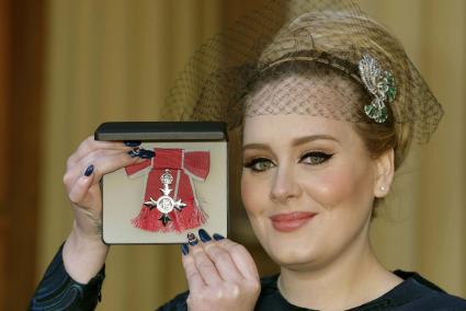 British singer Adele Adkins shows off her MBE for services to music presented to her by the Prince of Wales at Buckingham Palace