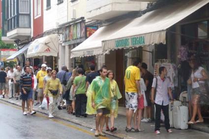 Ambientazo. Al no poder ir a la playa, los turistas aprovechan para visitar las poblaciones y realizar compras, incluso con el chubasquero - Elena