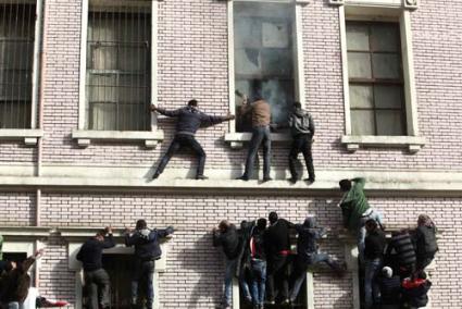 el cairo. Unos manifestantes escalan un edificio para apagar un fuego causado por un disparo de gas - Reuters