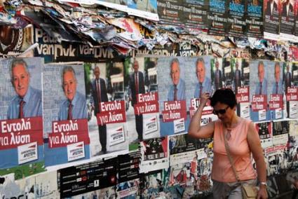 Atenas. Una mujer camina delante de una pared llena de carteles electorales - Reuters