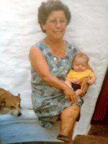 1979. Patio del Cementerio mahonés. Araceli Saura Crespo, sosteniendo entre sus brazos a su nieto Miguel Ángel Petrus Jordá. Observados por Perla, "sa cussa de sa família") foto cedida por Mari Jordá