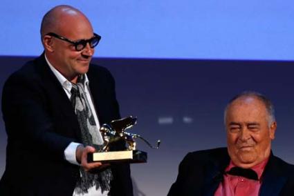 Gianfranco Rosi. El ganador del festival junto al director del jurado Bernardo Bertolucci - Reuters