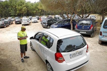 Un controlador intenta ordenar el tráfico en los accesos al parking de Cala en Turqueta.