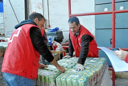 Voluntarios de Cruz Roja descargan los alimentos para su distribución entre personas sin recursos.