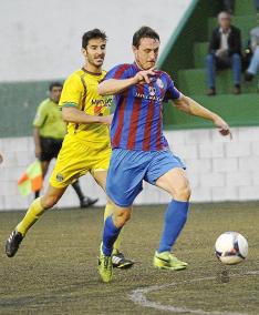 Óscar conduce el balón perseguido por Bili.