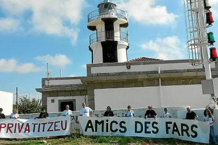 Representantes de la Asociación Amics des Fars, algunos de ellos venidos desde Mallorca, posan con las pancartas al pie del faro