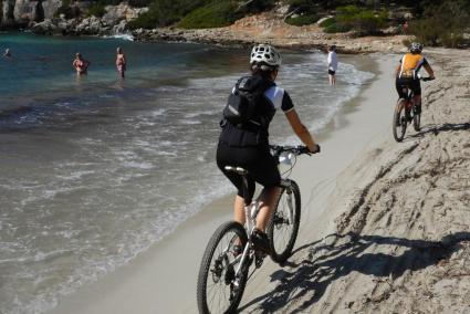 Un grupo de bañistas ve pasar a los ciclistas de la Volta