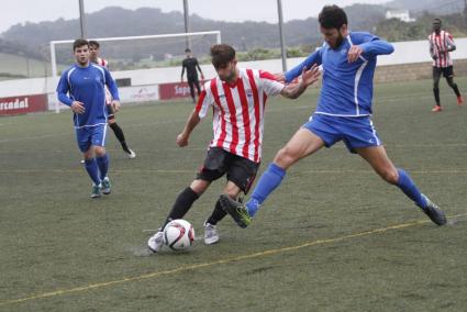 El centrocampista del Mercadal Izan golpea el balón ante la presencia de Nigorra del Binissalem