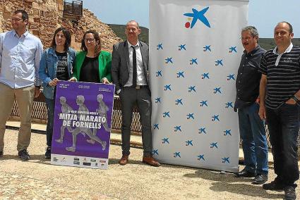 Oganizadores, promotores y autoridades posan en un marco exterior en Fornells con el cartel de la prueba.