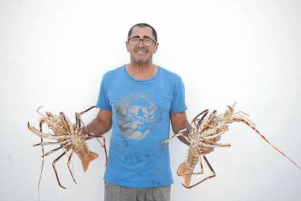 Un pescador sostiene dos grandes langostas a su llegada al puerto de Ciutadella