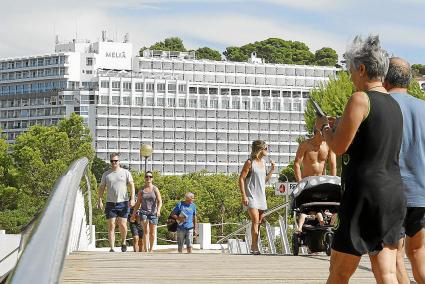 Turistas pasean por la urbanización de Cala Galdana, con uno de los hoteles al fondo.