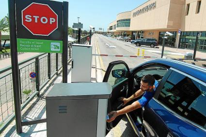 Un conductor obteniendo un ticket y, al fondo, coches aparcados en batería y en paralelo a la acera