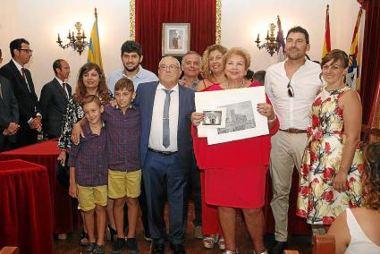 Maruja, junto a su familia, sostiene el grabado y el dibujo, obsequio del Ayuntamiento.