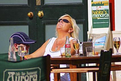 Imagen de archivo de una mujer en una terraza de Menorca, un día soleado.