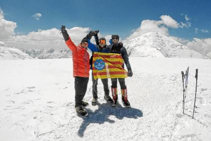 Iván Serra, Manel Coll y Francesc Oleo sostienen la bandera de Menorca en la cima del Razdelnaya.