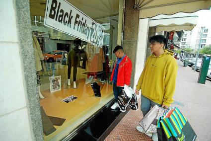 Compradores frente al escaparate de una de las tiendas de Maó que ofrece descuentos.