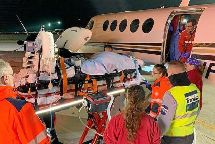 Personal sanitario introduce a un paciente en el interior de un avión ambulancia