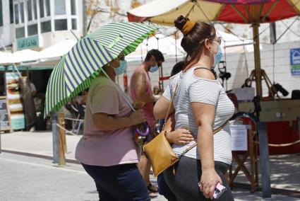 Una mujer se protege del sol con un paraguas, en Maó