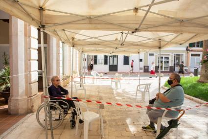 Una residente en el geriátrico municipal de Ciutadella recibe una visita bajo una carpa instalada en el exterior, en la Plaça Sant Antoni.