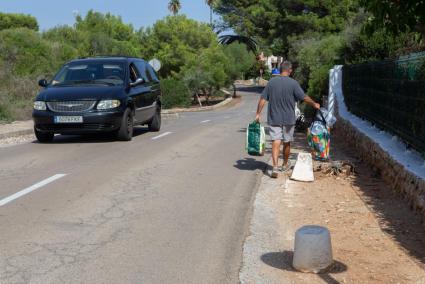 Una calle de la urbanización de calzada estrecha, sin aceras y con obstáculos.