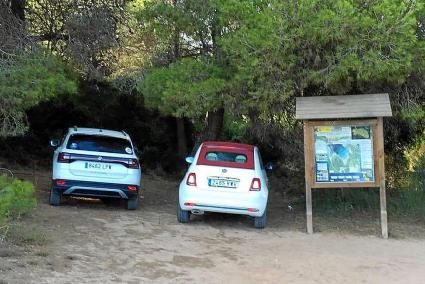 Dos coches estacionados junto a un cartel informativo de las playas de Algaiarens.