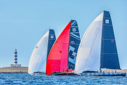 El barco líder de la competición de Maó tras la primera jornada, el ‘Alegre’ –el que está más a la izquierda en la fotografía–, pasando cerca del faro de la Illa de l’Aire, junto a otros dos contrincantes en la Isla, ‘Gladiator’ y ‘Platoon’