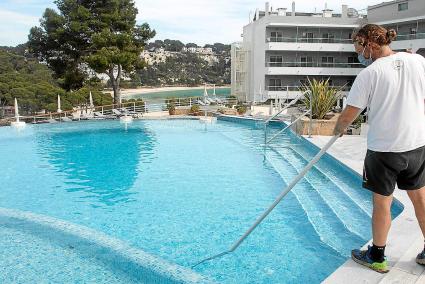 Un trabajador de un complejo hotelero en Cala Galdana pone a punto la piscina para recibir a los primeros clientes.