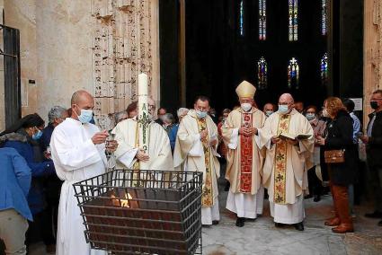 El obispo Joan Piris se dirige a encender el cirio pascual en la puerta principal de la Catedral.