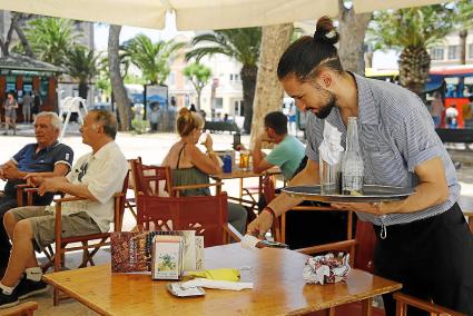 Un camarero recoge una mesa ayer en un bar de Ciutadella, donde muchos negocios cuelgan carteles buscando personal.