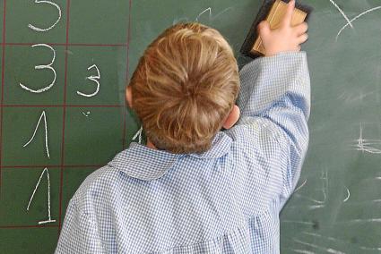 Un alumno de Primaria borra la pizarra durante una clase.