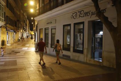 Una pareja paseando de noche por el centro de Maó.