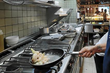 Un cocinero de un establecimiento de restauración saltea los alimentos en una sartén.