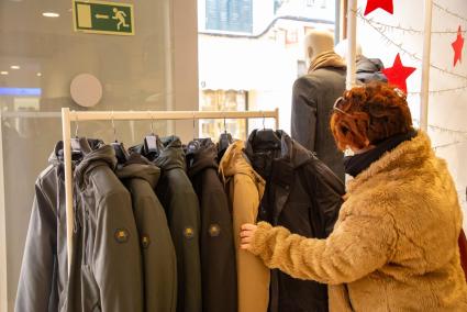 Una mujer mira abrigos y chaquetones expuestos en una tienda de Ciutadella.