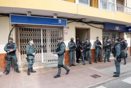 Un policía nacional y un guardia civil sacan a un detenido de un portal de la calle Sant Manuel, cortada al tráfico y repleta de efectivos policiales