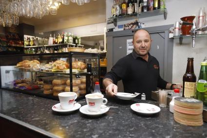 Un trabajador atiende a la clientela detrás de la barra de una cafetería en el centro de Maó.