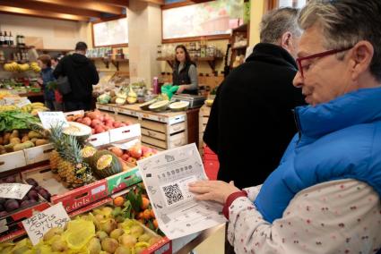 Una mujer, en una frutería, con los vales de compra, en el primer día que salieron