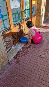 La presidenta del PP de Ciutadella, Juana Mari Pons, limpiando las pintadas de la sede del partido este sábado.