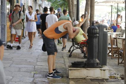 Un hombre se refresca este martes en una fuente del centro de Maó