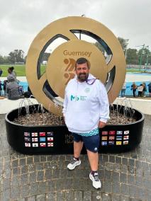 Kote Vidal, en Guernsey, delante de un logo gigante de los Island Games de 2023.