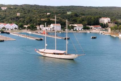 Un velero pasa frente a las instalaciones de la Base Naval de Maó.