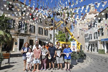 Usuaris del Centre Carlos Mir i membres de Consistori de Maó amb les banderetes reciclades instal·lades a la plaça del Príncep