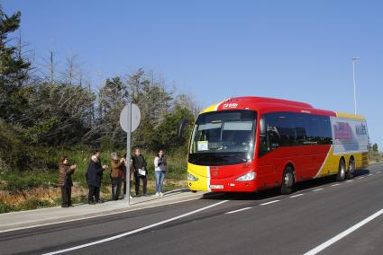 La comitiva oficial recibe con aplausos uno de los primeros buses que hace parada en la urbanización de Alaior.