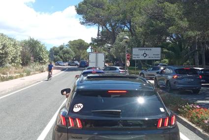 Un vehículo en la cola de salida de la urbanización, en dirección a Ferreries, esta semana.