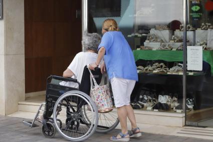 Una mujer pasea a otra en silla de ruedas por Maó. El perfil del solicitante de ayudas a la dependencia es mujer de 80 años o más .