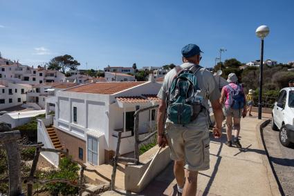 Un grupo de turistas pasean por la urbanización costera de Cala Torret, en el municipio de Sant Lluís.