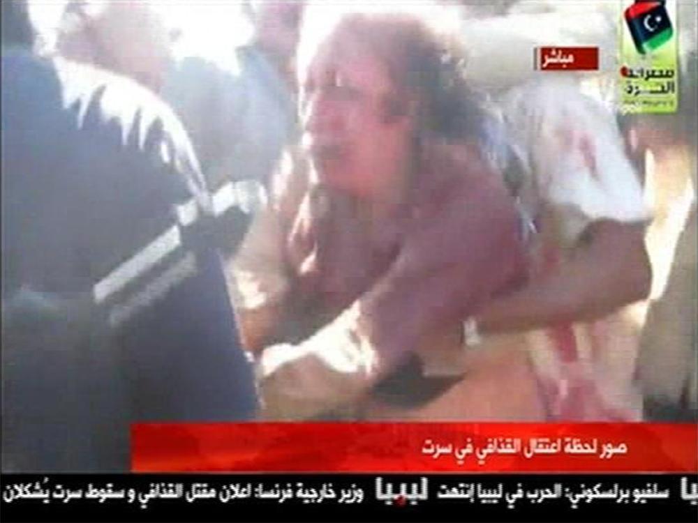 Frame grab of former Libyan leader Muammar Gaddafi, covered in blood, being pushed to the ground by NTC fighters in Sirte